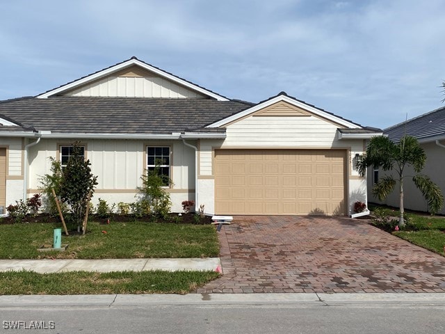 1023 Enbrook Loop, Naples, FL 34114 - ranch-style home with board and batten siding, decorative driveway, a garage, and a front lawn