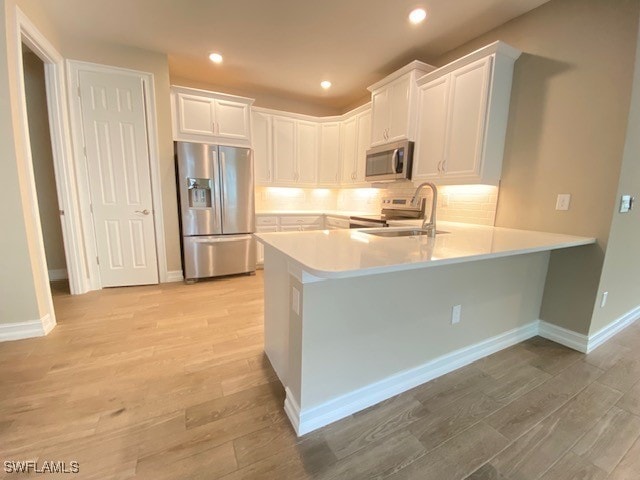 1023 Enbrook Loop, Naples, FL 34114 - kitchen featuring appliances with stainless steel finishes, a peninsula, light wood-type flooring, light countertops, and recessed lighting