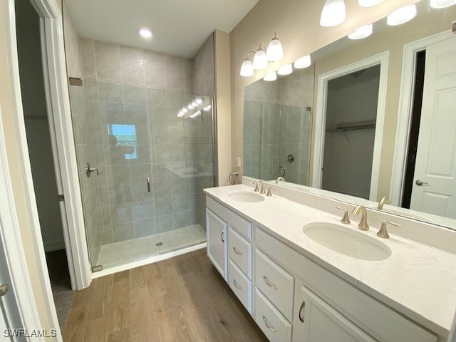 1023 Enbrook Loop, Naples, FL 34114 - bathroom featuring a stall shower, double vanity, a walk in closet, and wood finished floors