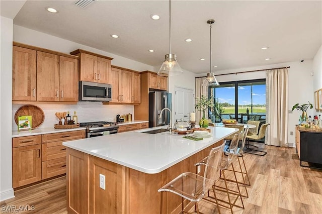 4563 Centaurus Cir, Naples, FL 34120 - kitchen featuring appliances with stainless steel finishes, light wood-type flooring, recessed lighting, a kitchen island with sink, and tasteful backsplash