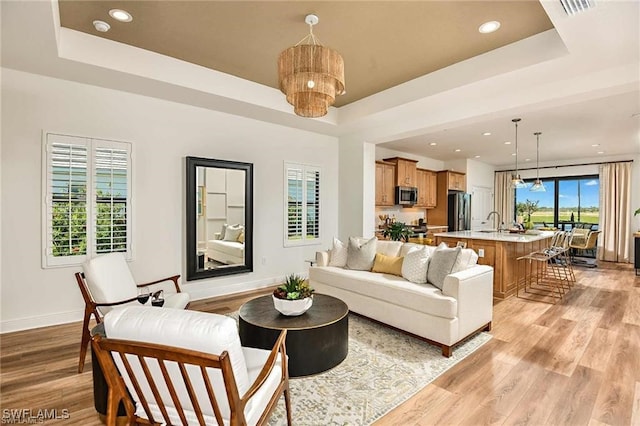 4563 Centaurus Cir, Naples, FL 34120 - living room featuring a raised ceiling, a chandelier, light wood finished floors, and recessed lighting