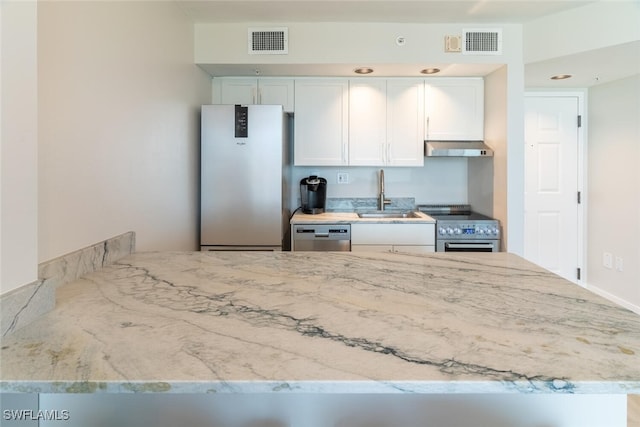 8771 Estero Blvd Unit 406, Fort Myers Beach, FL 33931 - kitchen with appliances with stainless steel finishes, exhaust hood, light stone counters, and white cabinets