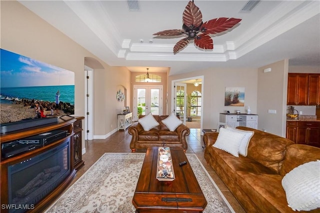 3606 Whippoorwill Blvd, Punta Gorda, FL 33950 - living room featuring a ceiling fan, a tray ceiling, arched walkways, ornamental molding, and dark tile patterned floors