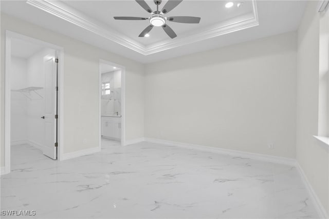 2718 42nd St W, Lehigh Acres, FL 33971 - unfurnished bedroom featuring a spacious closet, a tray ceiling, ornamental molding, marble finish flooring, and ensuite bathroom