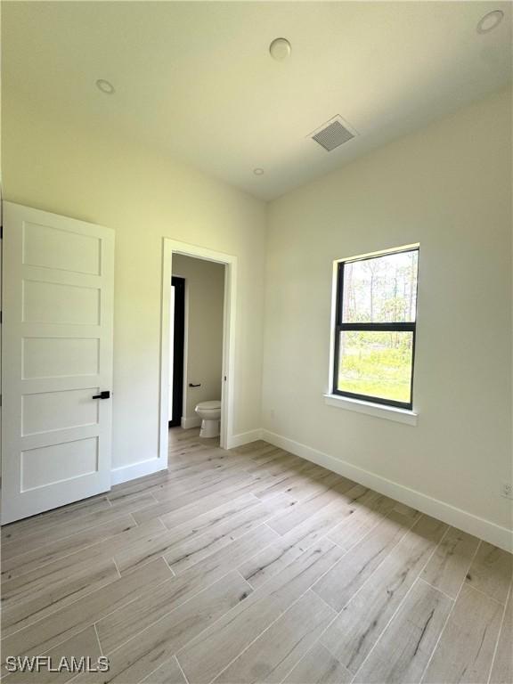 2660 18th Ave NE, Naples, FL 34120 - unfurnished bedroom featuring light wood-type flooring and connected bathroom