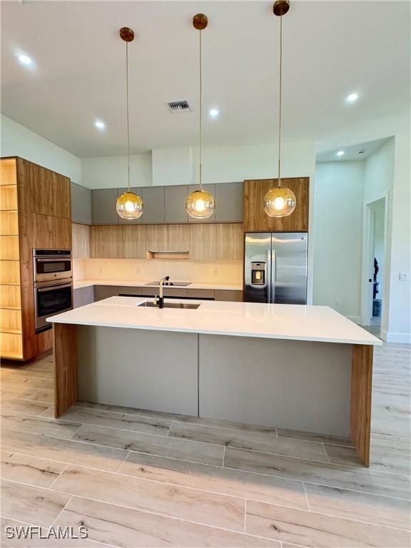 2660 18th Ave NE, Naples, FL 34120 - kitchen featuring stainless steel appliances, wood tiled floors, modern cabinets, a large island, and light countertops