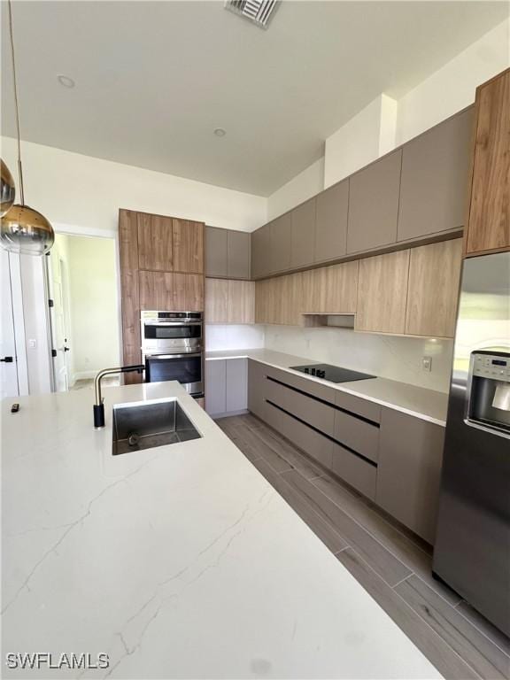 2660 18th Ave NE, Naples, FL 34120 - kitchen with stainless steel appliances, modern cabinets, light stone counters, and wood finish floors
