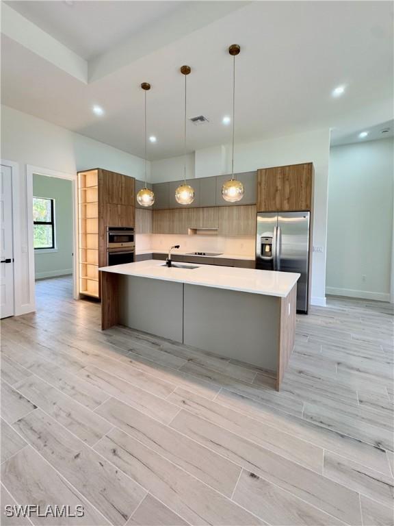 2660 18th Ave NE, Naples, FL 34120 - kitchen featuring appliances with stainless steel finishes, light countertops, light wood-type flooring, recessed lighting, and a large island with sink