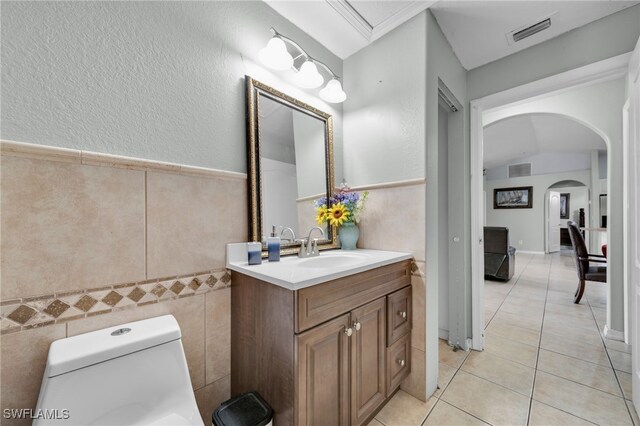 3031 36th St SW, Lehigh Acres, FL 33976 - bathroom featuring tile patterned floors, tile walls, vanity, a textured wall, and a wainscoted wall