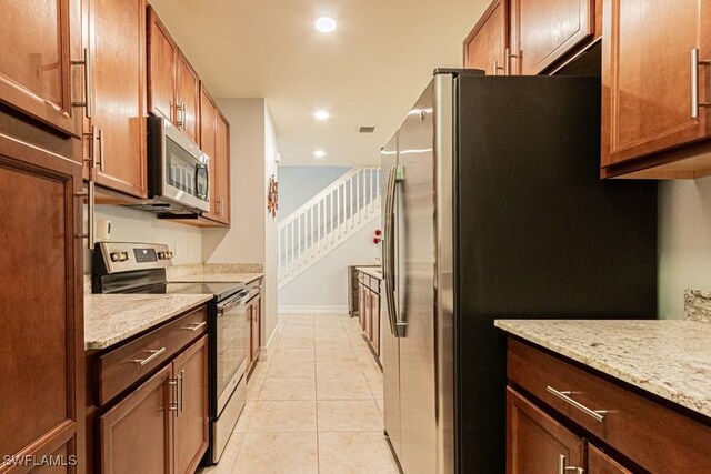 7907 Bristol Cir, Naples, FL 34120 - kitchen featuring stainless steel appliances, recessed lighting, light tile patterned floors, light stone counters, and brown cabinetry