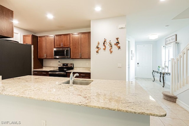 7907 Bristol Cir, Naples, FL 34120 - kitchen with stainless steel appliances, light stone countertops, light tile patterned flooring, recessed lighting, and brown cabinetry