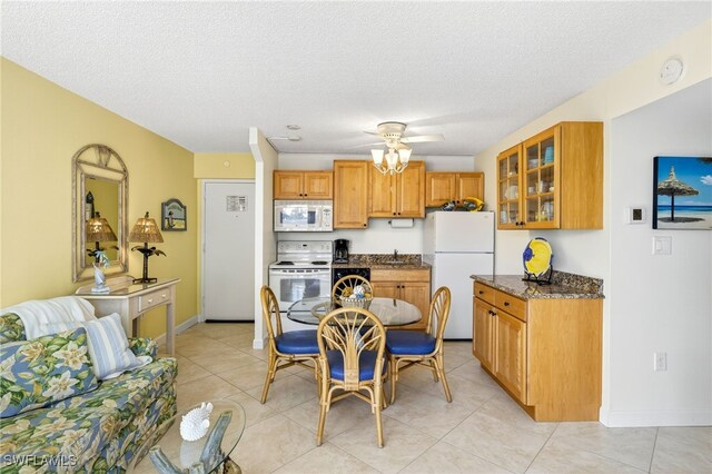 8701 Estero Blvd Unit 105, Bonita Springs, FL 33931 - kitchen with white appliances, glass insert cabinets, brown cabinets, dark stone countertops, and light tile patterned floors