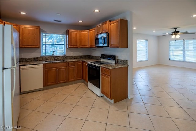 180 Cypress Way E Unit B212, Naples, FL 34110 - kitchen featuring white appliances, brown cabinetry, recessed lighting, light tile patterned floors, and dark stone countertops
