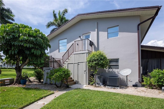 180 Cypress Way E Unit B212, Naples, FL 34110 - rear view of house featuring stairway, a yard, stucco siding, and a balcony