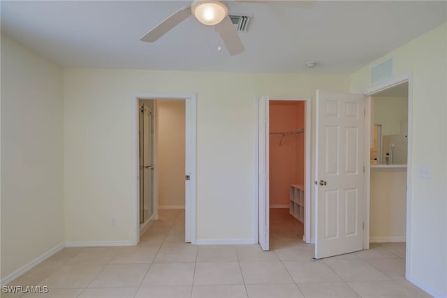 304 NW 22nd Ave, Cape Coral, FL 33993 - unfurnished bedroom featuring white refrigerator with ice dispenser, light tile patterned floors, a walk in closet, a closet, and ceiling fan