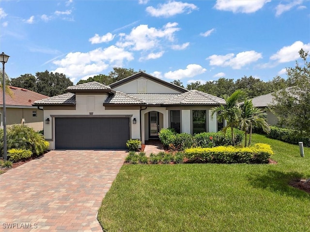 16569 Windsor Way, Alva, FL 33920 - view of front facade featuring stucco siding, a front lawn, an attached garage, a tiled roof, and decorative driveway