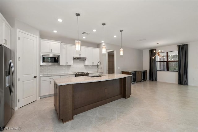 16569 Windsor Way, Alva, FL 33920 - kitchen with appliances with stainless steel finishes, a chandelier, under cabinet range hood, decorative backsplash, and white cabinetry