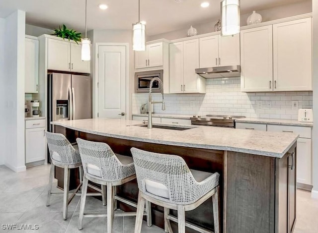16569 Windsor Way, Alva, FL 33920 - kitchen featuring appliances with stainless steel finishes, under cabinet range hood, tasteful backsplash, an island with sink, and recessed lighting