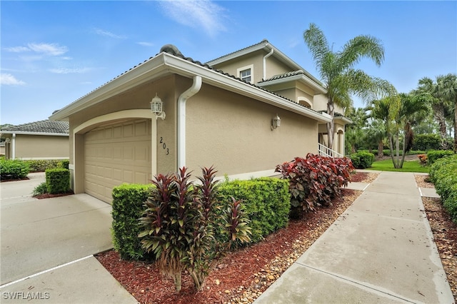 3425 Laurel Greens Ln S Unit 203, Naples, FL 34119 - view of property exterior with stucco siding, an attached garage, and concrete driveway