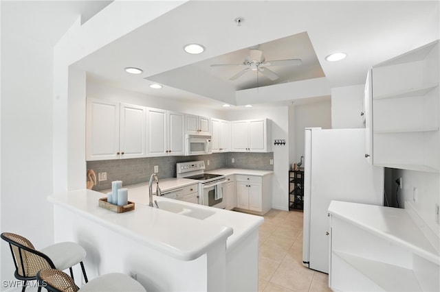 3425 Laurel Greens Ln S Unit 203, Naples, FL 34119 - kitchen with white appliances, a breakfast bar area, ceiling fan, tasteful backsplash, and recessed lighting