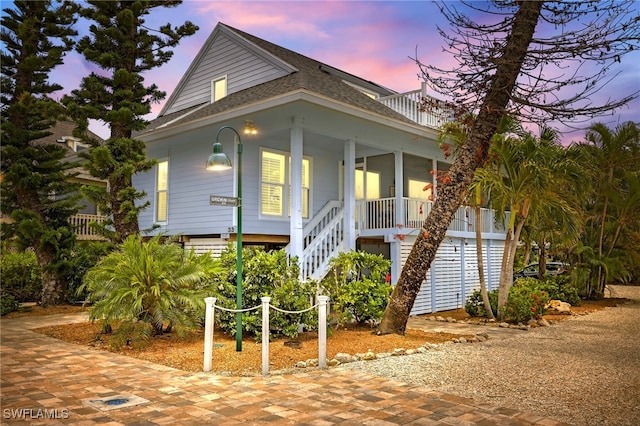 33 Urchin Ct, Captiva, FL 33924 - coastal home featuring stairs, a shingled roof, and covered porch