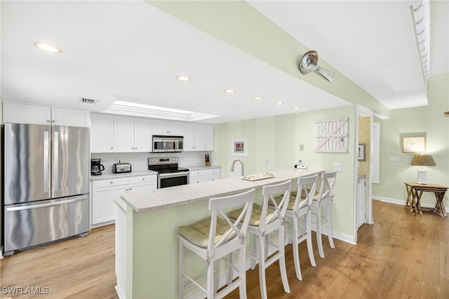 33 Urchin Ct, Captiva, FL 33924 - kitchen with appliances with stainless steel finishes, a breakfast bar area, white cabinets, light wood-type flooring, and recessed lighting