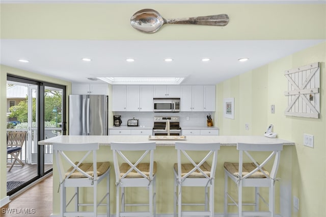 33 Urchin Ct, Captiva, FL 33924 - kitchen featuring appliances with stainless steel finishes, a breakfast bar area, light countertops, recessed lighting, and white cabinets