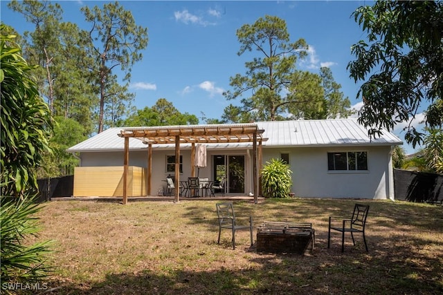 5870 Star Grass Ln, Naples, FL 34116 - rear view of house featuring stucco siding, an outdoor fire pit, a pergola, a metal roof, and a yard