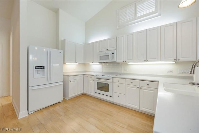 2457 Dorset Ct, Naples, FL 34112 - kitchen with white appliances, high vaulted ceiling, light wood-type flooring, and white cabinets