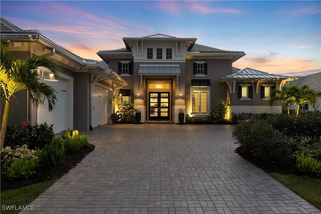 8923 Nevis Way, Naples, FL 34112 - view of front facade with french doors, decorative driveway, stucco siding, and an attached garage