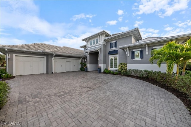 8923 Nevis Way, Naples, FL 34112 - view of front of home featuring stucco siding, decorative driveway, and a garage