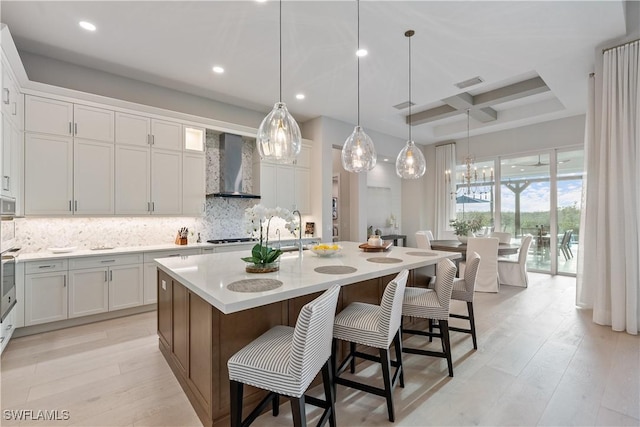 8923 Nevis Way, Naples, FL 34112 - kitchen with wall chimney range hood, coffered ceiling, tasteful backsplash, light countertops, and a kitchen bar