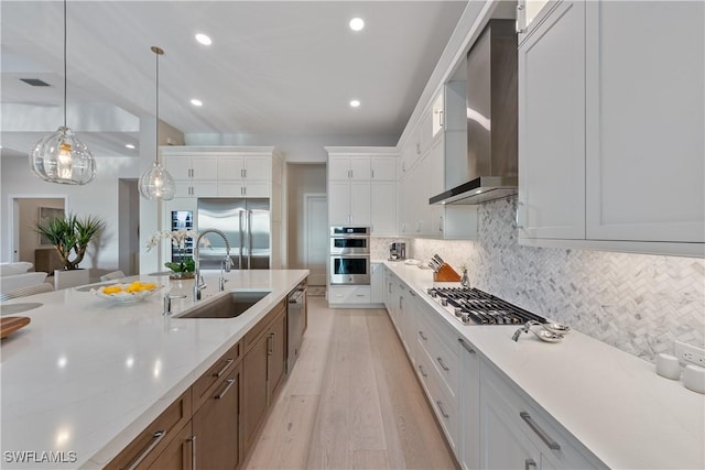 8923 Nevis Way, Naples, FL 34112 - kitchen featuring wall chimney range hood, stainless steel appliances, white cabinetry, light wood finished floors, and decorative backsplash