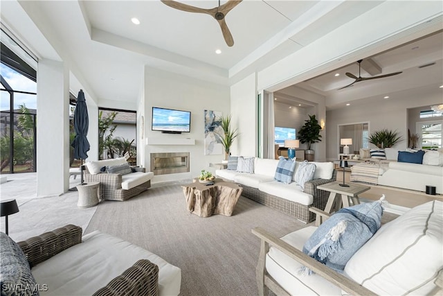 8923 Nevis Way, Naples, FL 34112 - living room featuring a ceiling fan, a glass covered fireplace, recessed lighting, and a tray ceiling