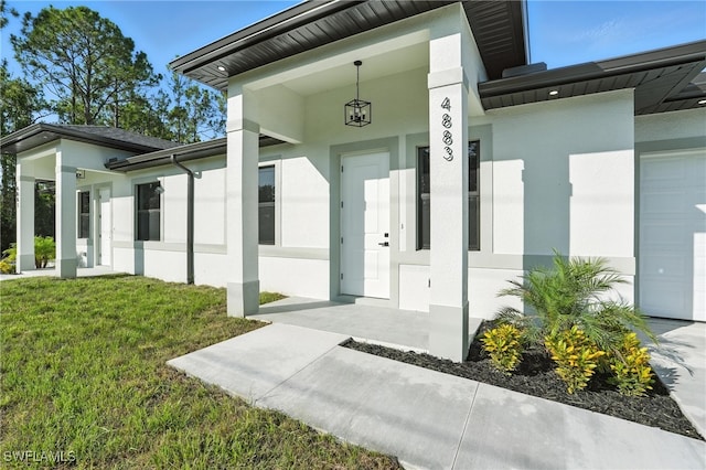 4881/4883 Leonard Blvd S, Lehigh Acres, FL 33973 - entrance to property featuring stucco siding, a garage, a yard, and covered porch