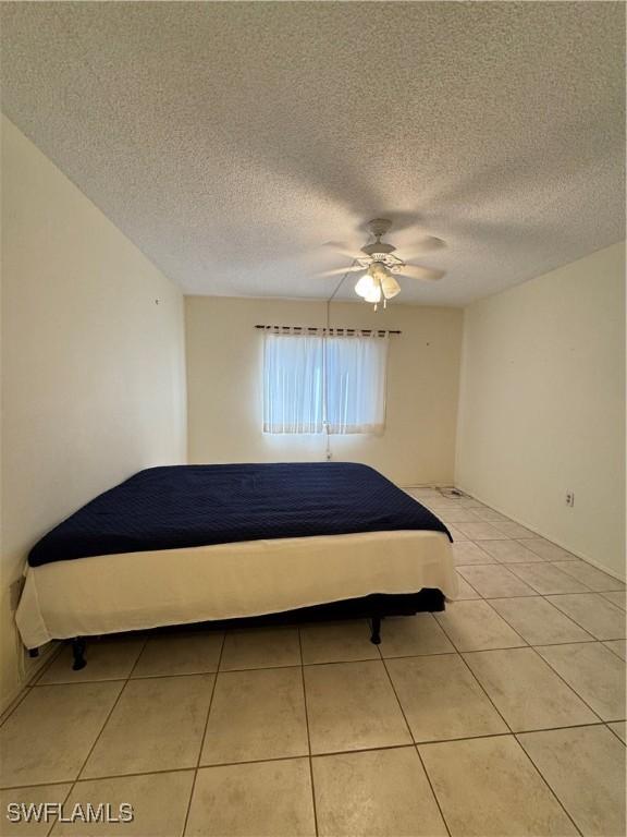 1069 Villa Dr Unit B103, Labelle, FL 33935 - bedroom featuring light tile patterned flooring, ceiling fan, and a textured ceiling