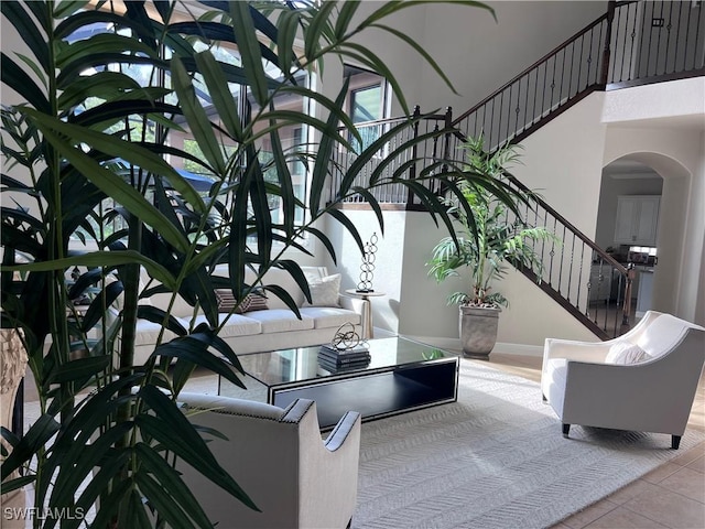 23056 Sanabria Loop, Bonita Springs, FL 34135 - tiled living room featuring arched walkways, stairs, and a towering ceiling