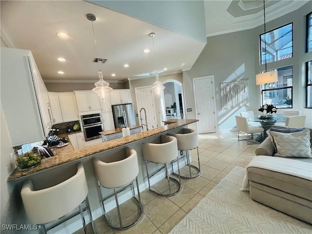 23056 Sanabria Loop, Bonita Springs, FL 34135 - kitchen featuring arched walkways, a breakfast bar, appliances with stainless steel finishes, crown molding, and open floor plan