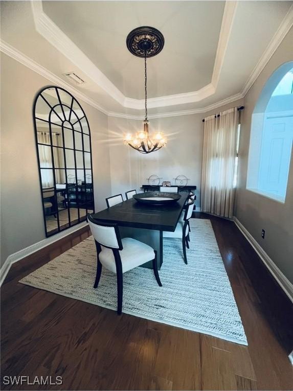 23056 Sanabria Loop, Bonita Springs, FL 34135 - dining room with a raised ceiling, arched walkways, dark wood-style floors, a chandelier, and crown molding