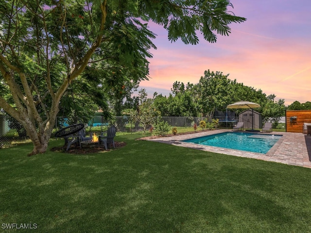 446 SW 19th Ter, Cape Coral, FL 33991 - pool at dusk with a storage unit, a fenced backyard, an outdoor fire pit, and a patio