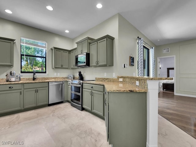 446 SW 19th Ter, Cape Coral, FL 33991 - kitchen featuring appliances with stainless steel finishes, green cabinetry, a peninsula, light stone counters, and recessed lighting