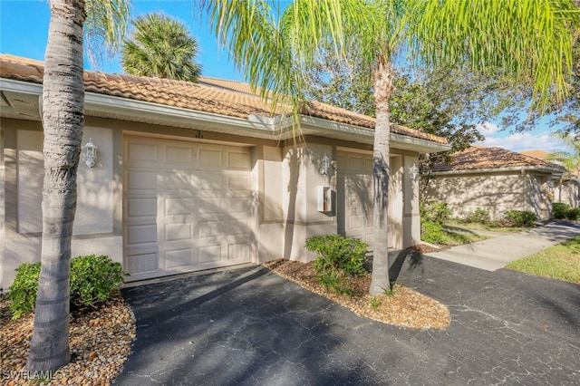 1128 Manor Lake Dr Unit G103, Naples, FL 34110 - view of side of home featuring stucco siding, a tile roof, and asphalt driveway
