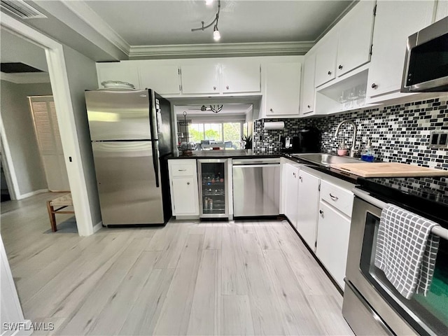 34 Glades Blvd Unit 1461, Naples, FL 34112 - kitchen with stainless steel appliances, wine cooler, dark countertops, white cabinetry, and crown molding