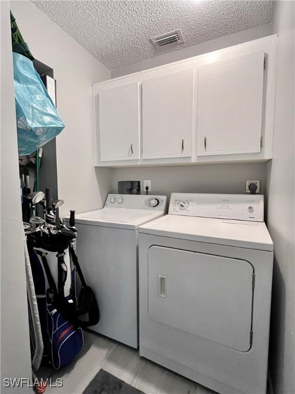 34 Glades Blvd Unit 1461, Naples, FL 34112 - washroom featuring independent washer and dryer, cabinet space, and a textured ceiling