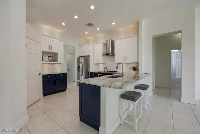 1087 Port Orange Way, Naples, FL 34120 - kitchen featuring wall chimney exhaust hood, stainless steel fridge with ice dispenser, recessed lighting, light tile patterned floors, and light stone countertops