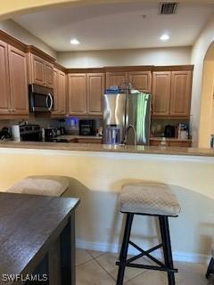 4400 Lazio Way Unit 201, Fort Myers, FL 33901 - kitchen with appliances with stainless steel finishes, arched walkways, recessed lighting, a breakfast bar, and light tile patterned floors