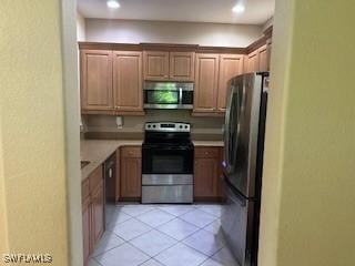 4400 Lazio Way Unit 201, Fort Myers, FL 33901 - kitchen featuring stainless steel appliances, light tile patterned flooring, and light countertops