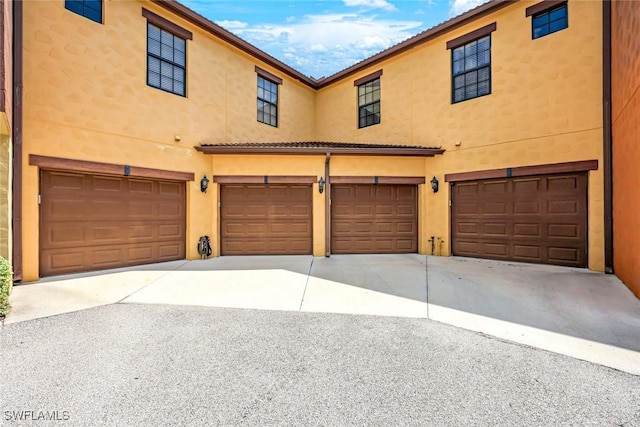 11758 Izarra Way Unit 7703, Fort Myers, FL 33912 - townhome / multi-family property with an attached garage, stucco siding, and driveway