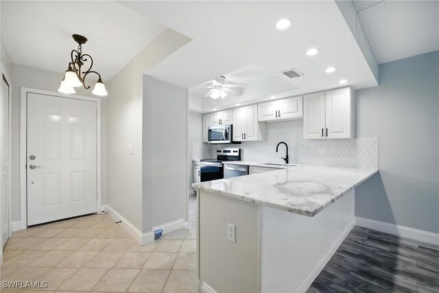 16001 Dublin Cir Unit 103, Fort Myers, FL 33908 - kitchen featuring stainless steel appliances, recessed lighting, backsplash, white cabinetry, and a peninsula