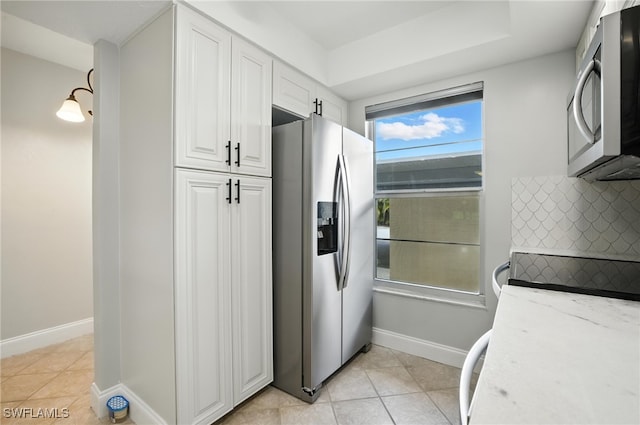 16001 Dublin Cir Unit 103, Fort Myers, FL 33908 - kitchen featuring appliances with stainless steel finishes, white cabinetry, decorative backsplash, light tile patterned flooring, and light stone counters